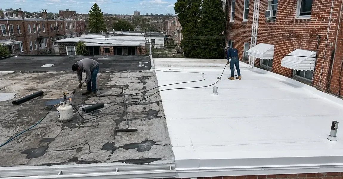Worn dark bitumen flat roof beside a new white reflective roof membrane